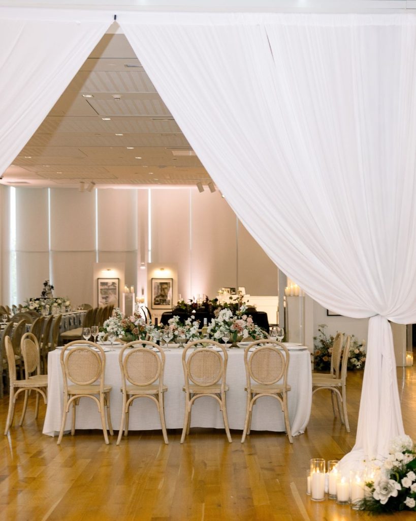 White drapes frame a floral reception table with cane back chairs at the Columbus Museum of Art.