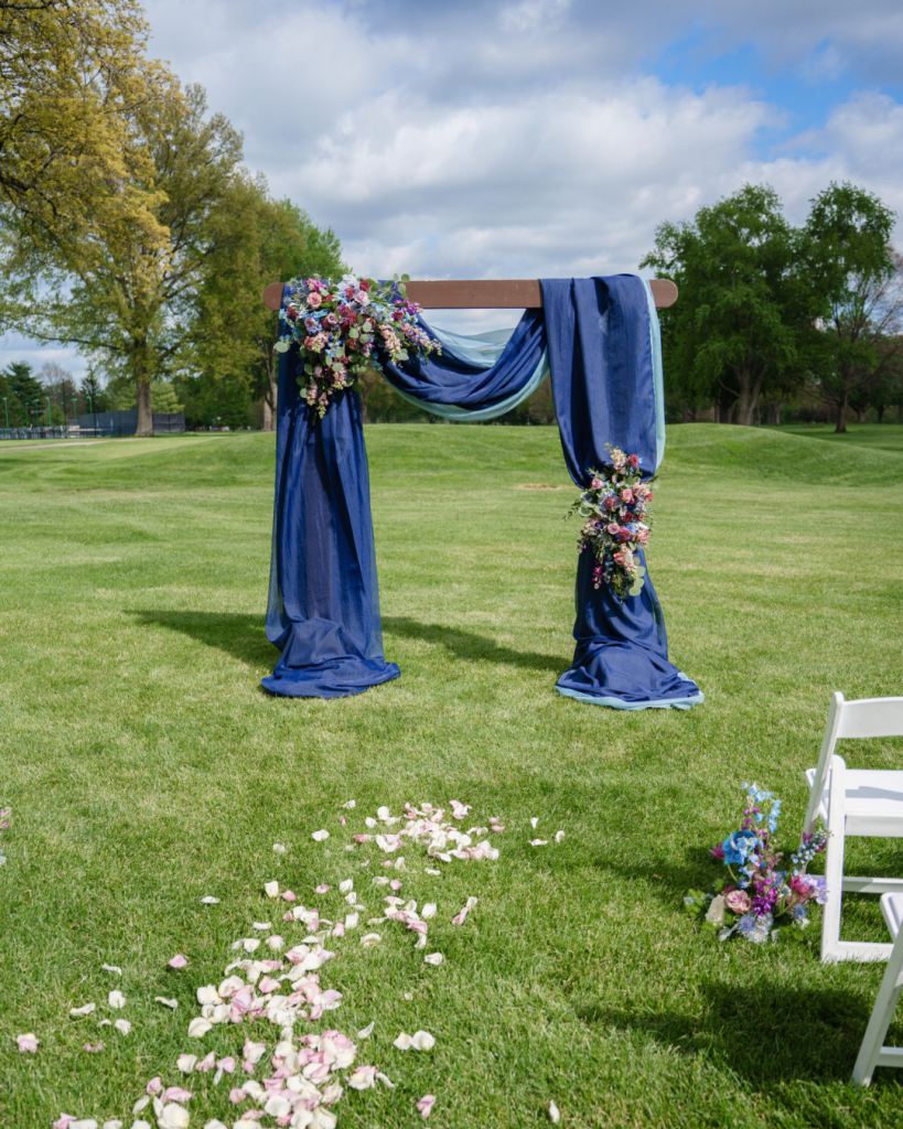 Outdoor wedding ceremony at Brookside Golf & Country Club with navy draping, colorful flowers and petals lining the aisle.