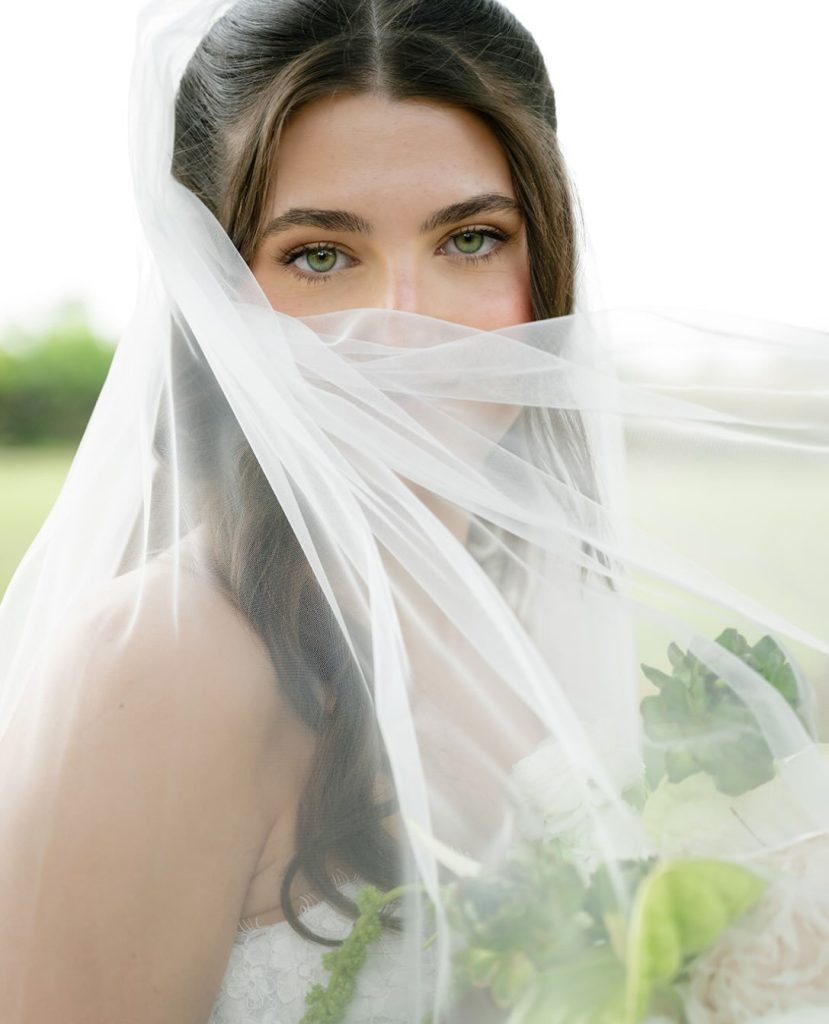 Close-up of bride's face through a flowing veil outdoors