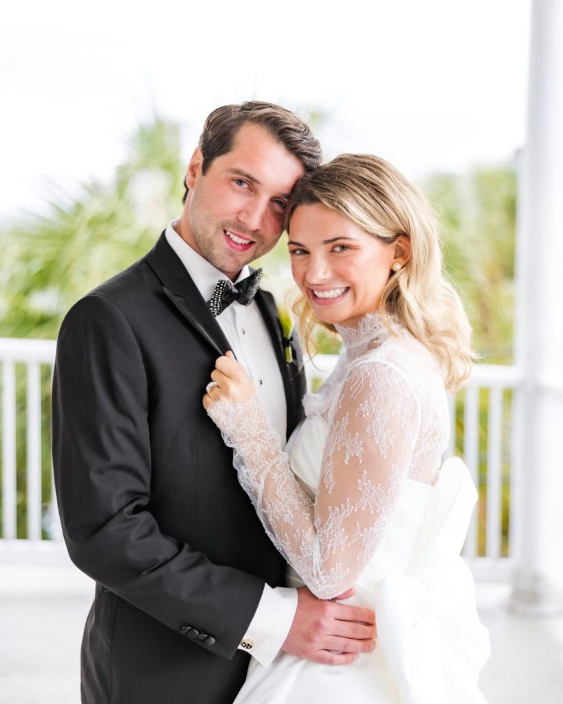 Close-up portrait of the bride and groom smiling together outdoors on a balcony.