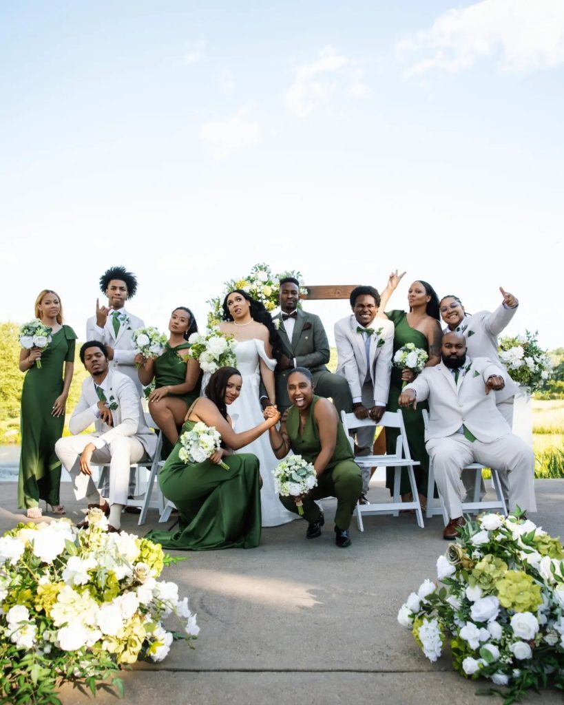 wedding party posing together in front of wedding ceremony wooden arch near pond in loudoun county wedding venue