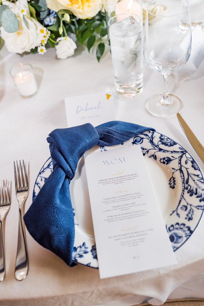 wedding tablescape with blue and white design with custom menu and greenery around virginia wedding venue