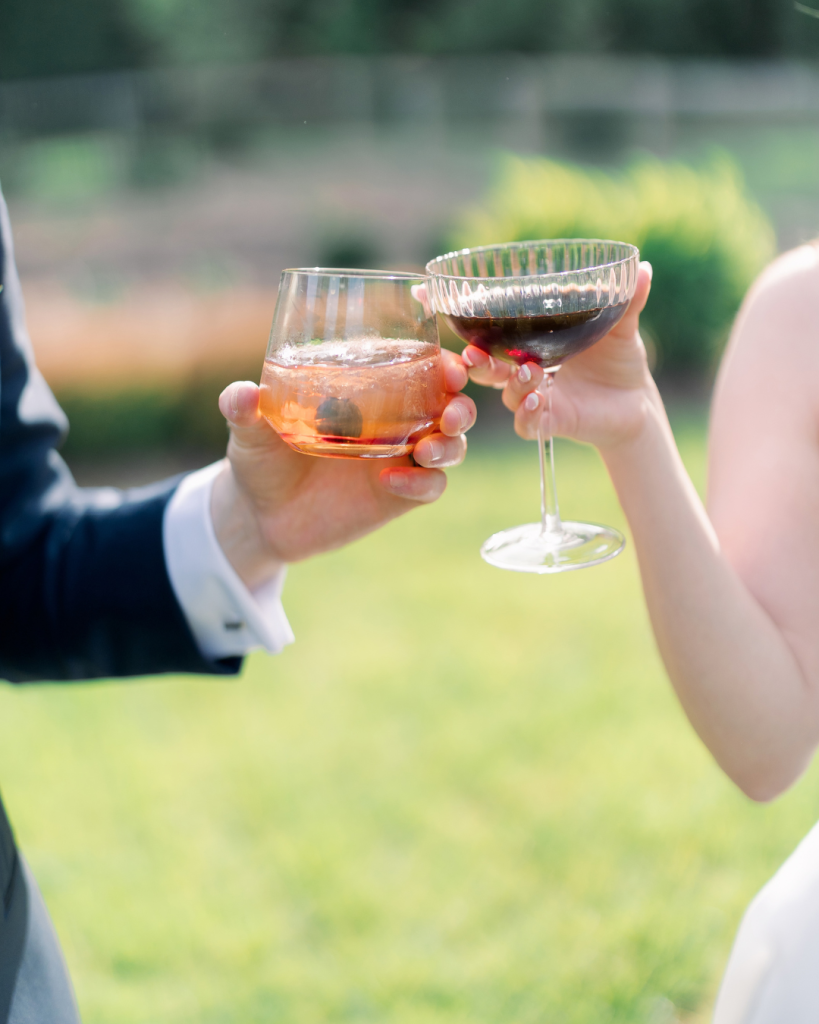 Emma and Cameron toast with cocktails during their spring wedding celebration at Splendor Pond in Mooresville, North Carolina.