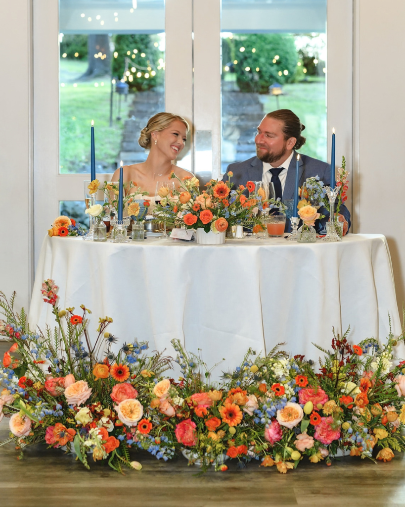 wedding reception bride and groom at sweetheart table with colorful flowers