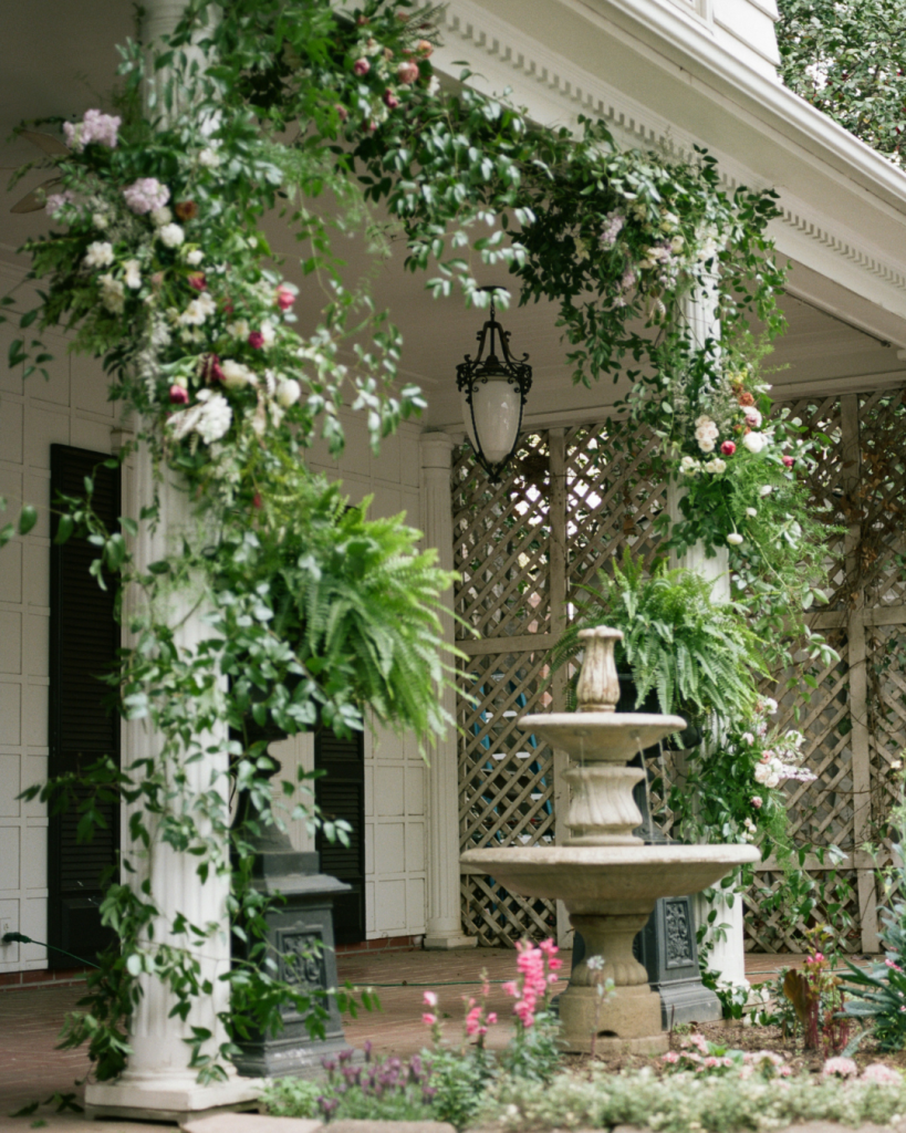 Lush garden inspired wedding florals frame the white columns and fountain at The Morehead Inn in Charlotte.