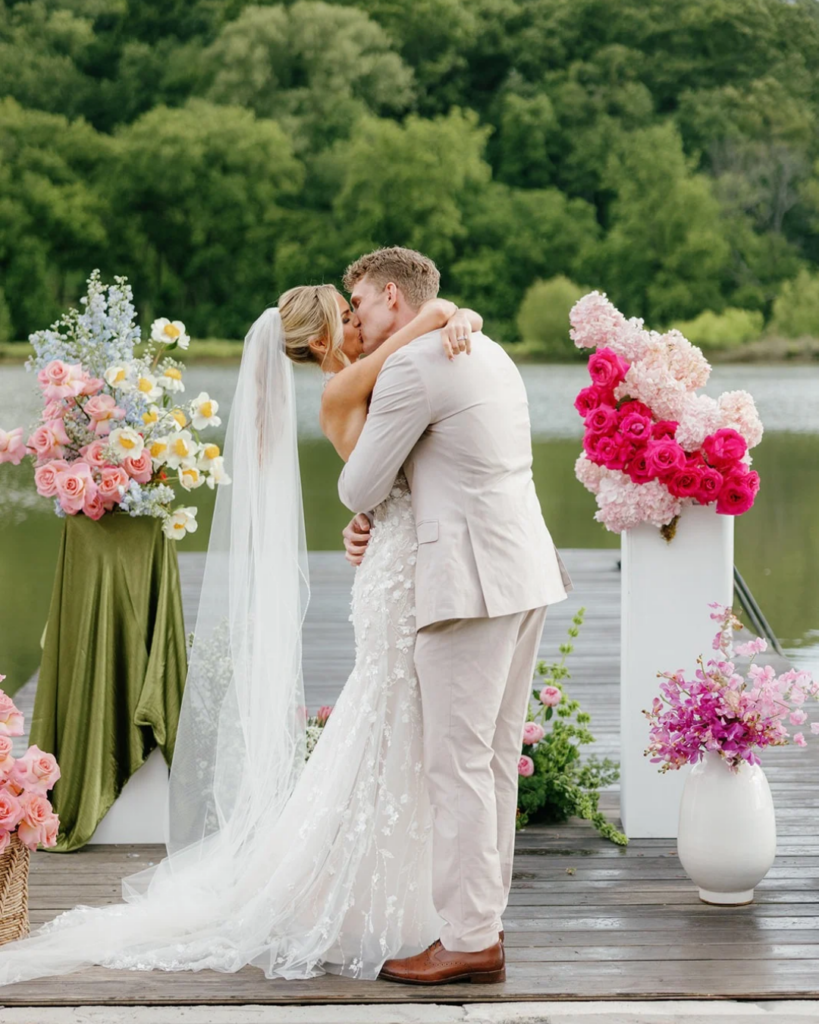 Couple kissing in front of lake at wedding ceremony