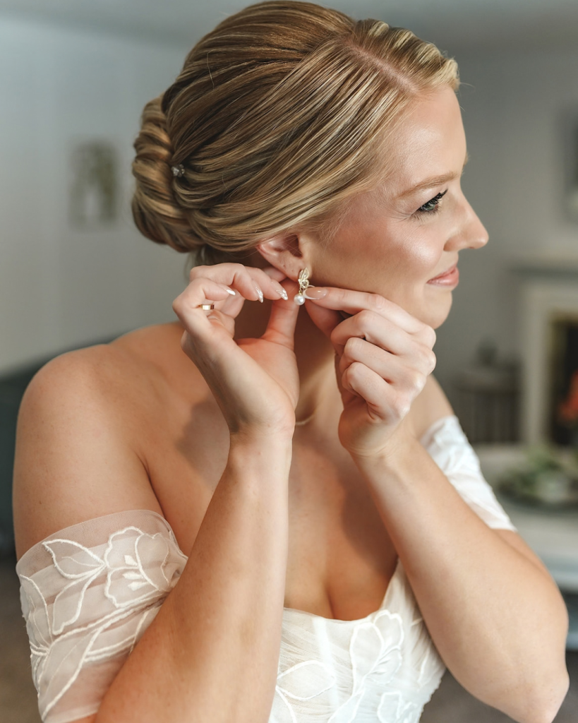 bride getting for her wedding putting her earring in