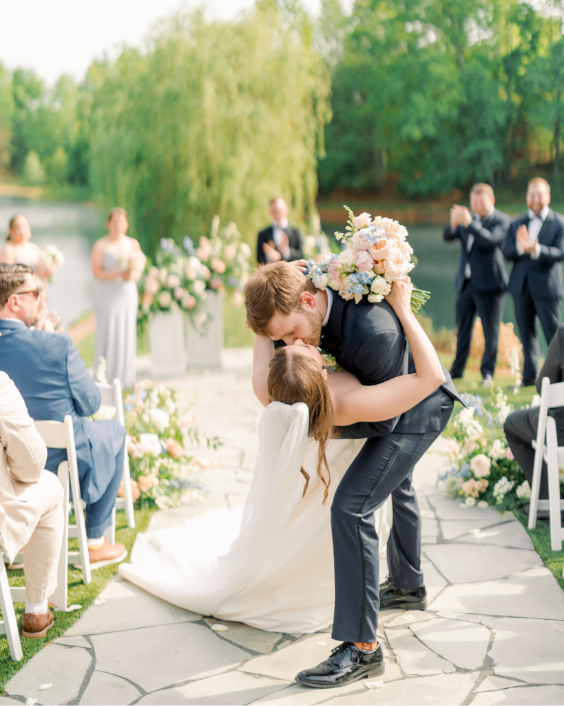 Emma and Cameron share a celebratory dip and kiss after their outdoor wedding ceremony beside the water at Splendor Pond.
