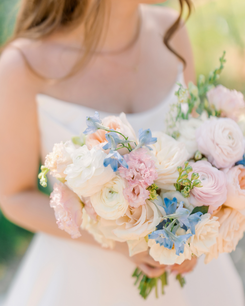 Close view of Emma’s spring bridal bouquet featuring peach, blush, white and soft blue flowers.
