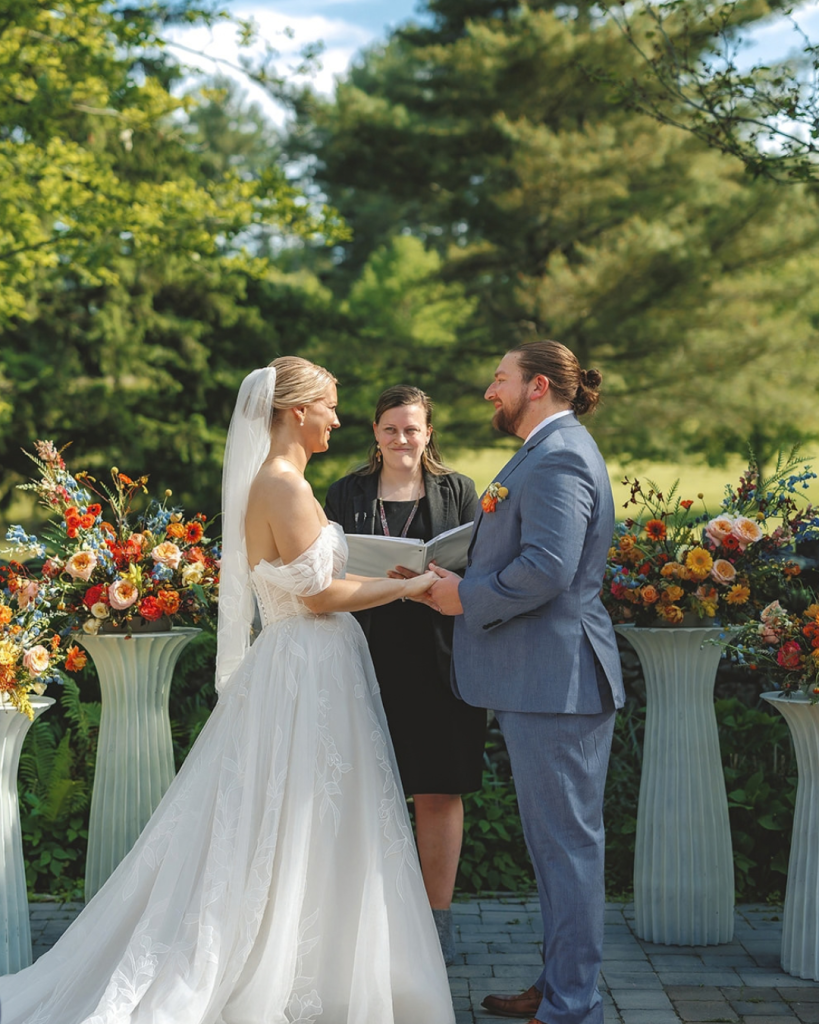 wedding ceremony with officiant holding book and bride and groom holding hands