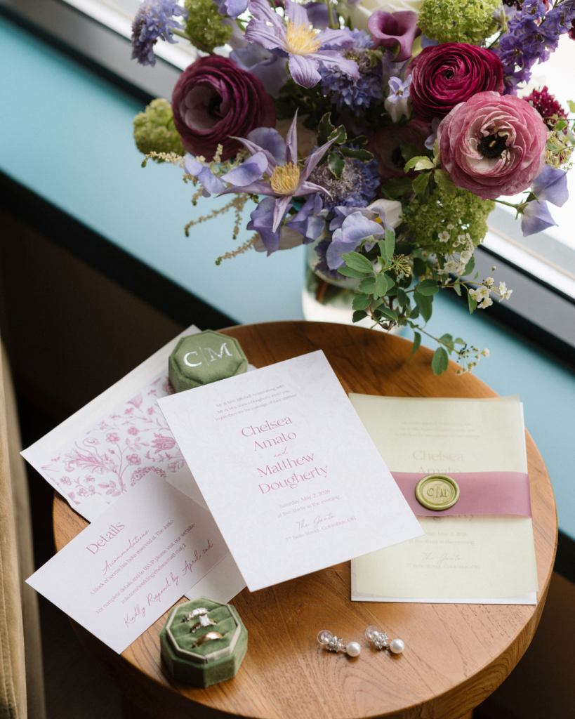 Pink and purple bridal bouquet beside personalized wedding invitations and green velvet ring boxes for Chelsea and Matt's Columbus wedding