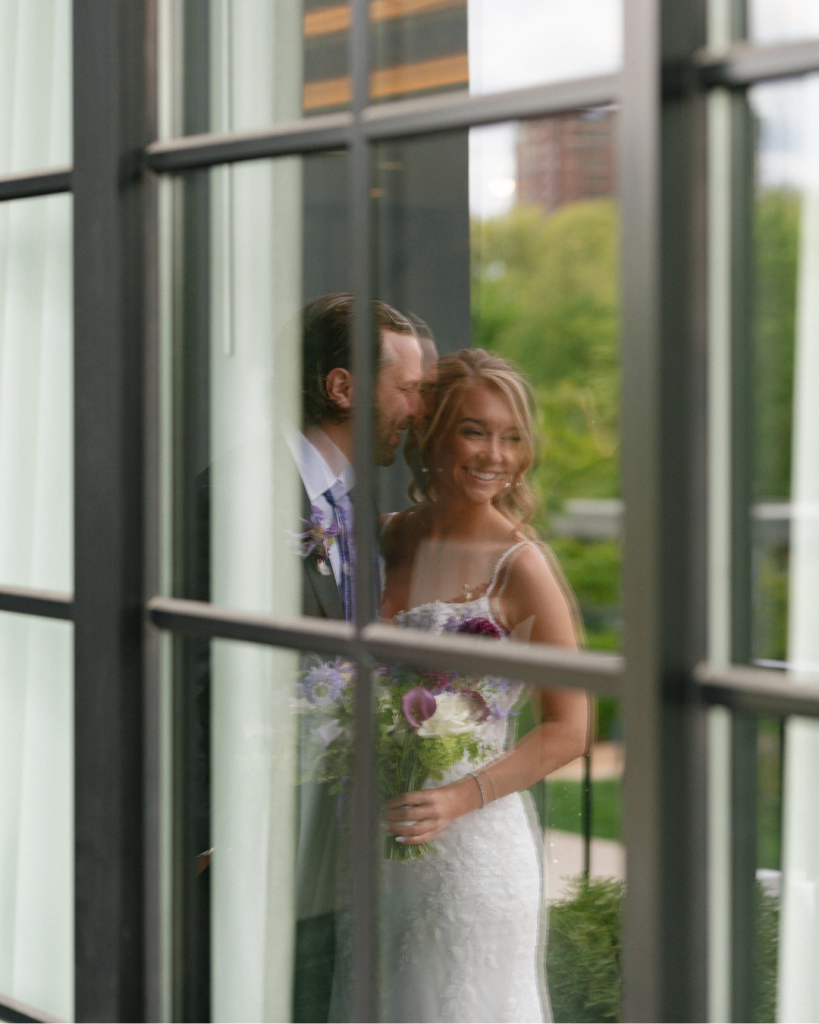 Newlyweds Chelsea and Matt share a romantic moment behind glass windows at The Junto wedding venue in Columbus, Ohio.