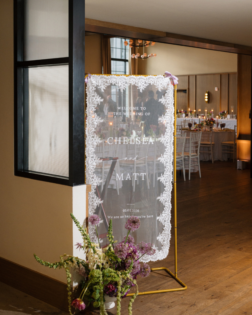 Custom lace wedding welcome sign for Chelsea and Matt surrounded by colorful flowers at The Junto in Columbus, Ohio