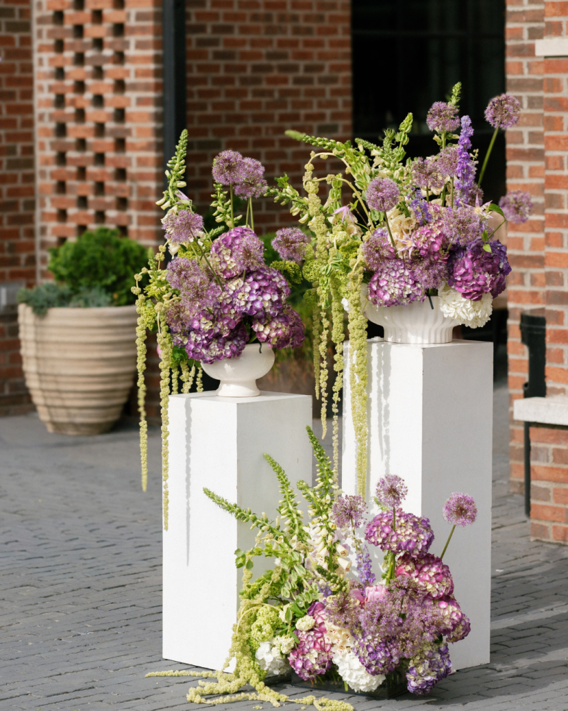 Statement purple hydrangea and green floral arrangements displayed on white ceremony pedestals at The Junto in Columbus, Ohio