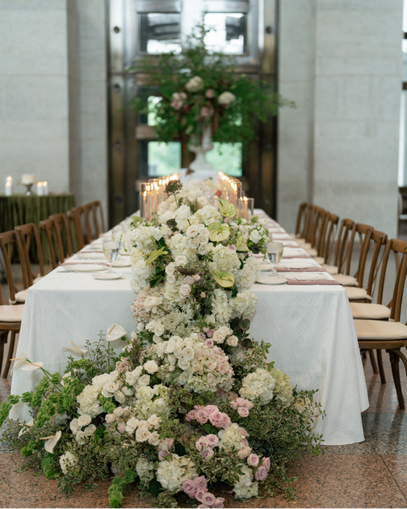 Elegant wedding head table with cascading white hydrangeas, soft pink roses, greenery and glowing candles at The Ohio Statehouse in Columbus.