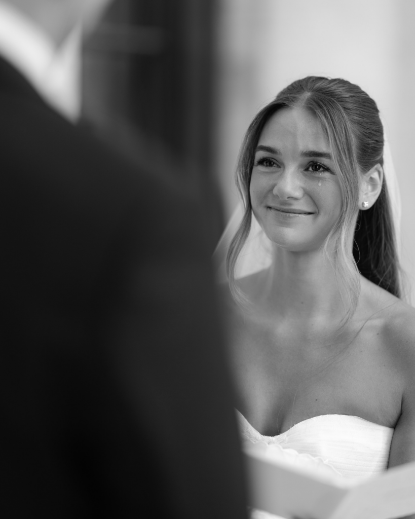 Emotional bride Hannah smiles through tears while looking at groom Ben during their wedding ceremony in Columbus, Ohio.