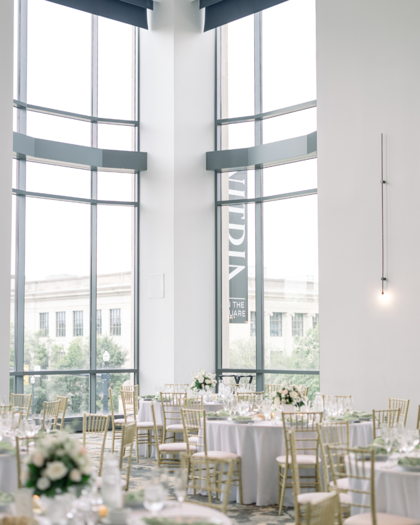 Wedding reception at Vitria on the Square in Columbus with soaring windows, white floral centerpieces, sage napkins and gold chairs.