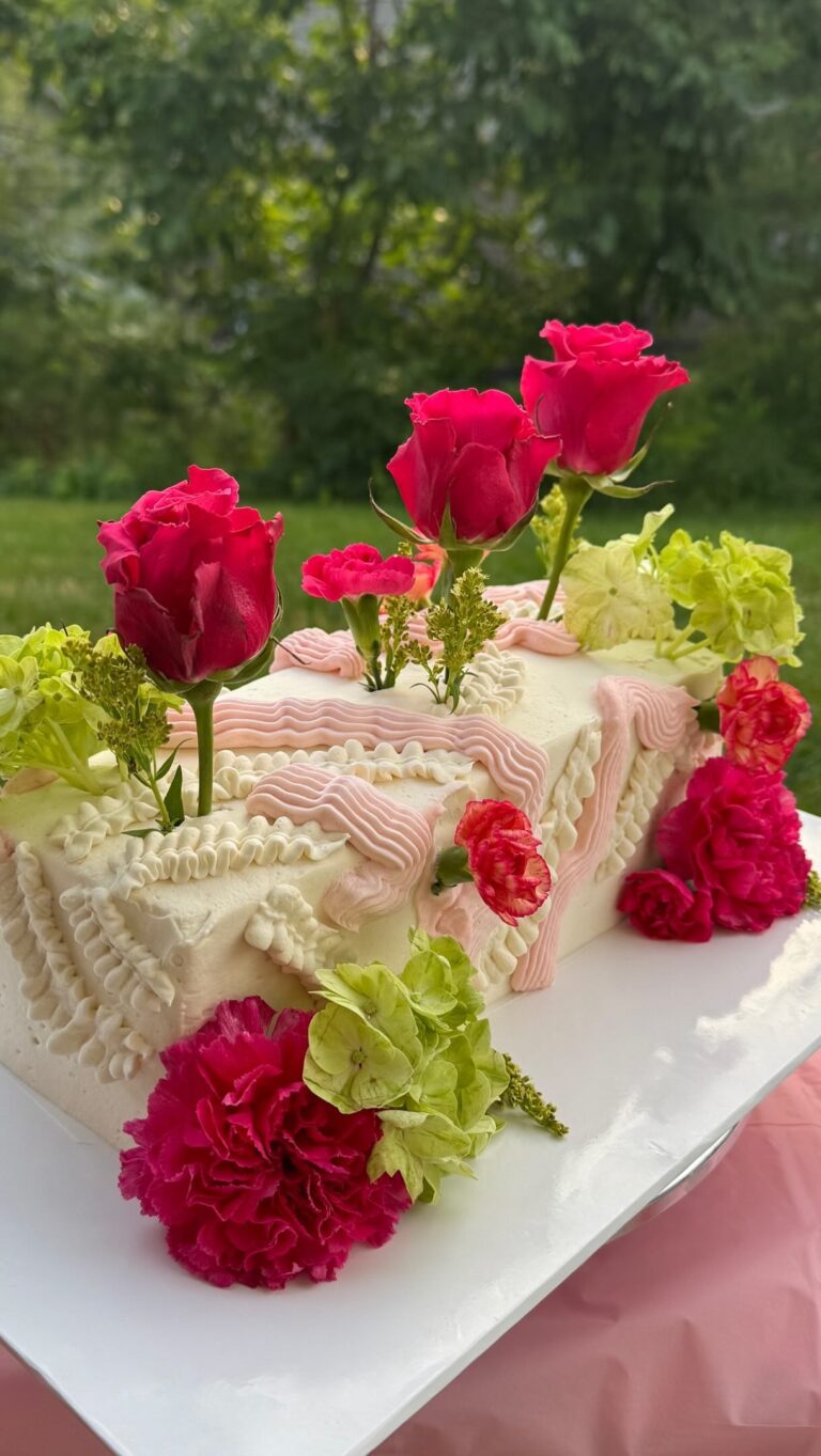Helu Sweets Bakery romantic rectangular cake featuring delicate ivory and blush pink buttercream piping, vibrant pink roses, pink carnations, and soft green floral accents.