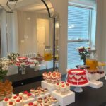 Helu Sweets Bakery custom dessert table featuring a red and white vintage-style cake, individual strawberry desserts, mini cheesecakes, cupcakes, and layered sweet treats arranged on elegant white display stands.