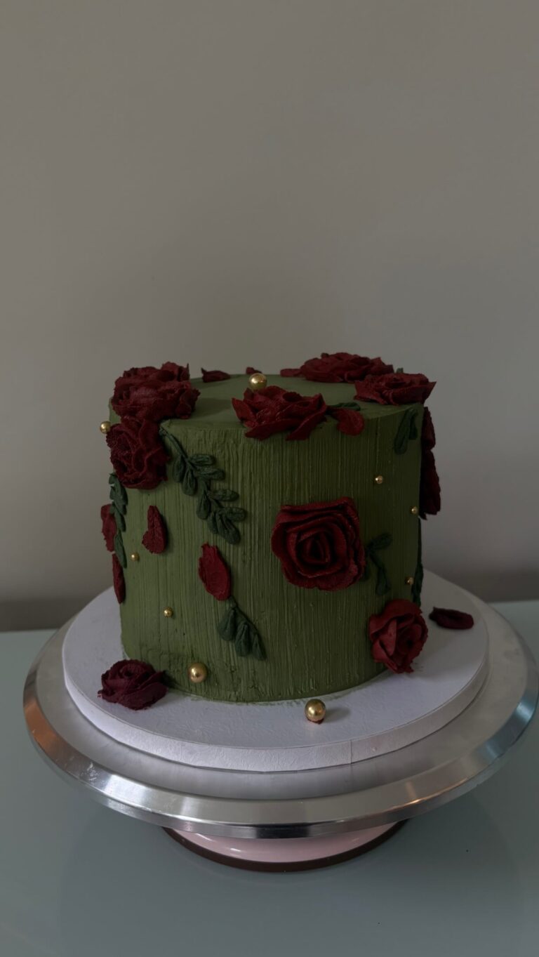 Helu Sweets Bakery custom dark green cake featuring textured buttercream frosting, deep burgundy buttercream roses, delicate green leaves, and elegant gold pearl accents.