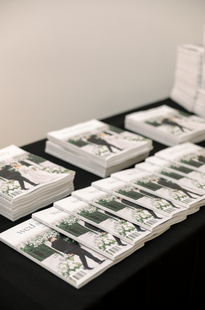 Stacks of the inaugural 2026 Wed Society | Columbus Book of Weddings magazines displayed at the Columbus Museum of Art release celebration, featuring elegant wedding photography on the covers.
