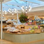 Interior of Littleton’s Market in Upper Arlington, Ohio, featuring a gourmet bakery display with fresh breads, pastries, desserts, and modern globe chandeliers.