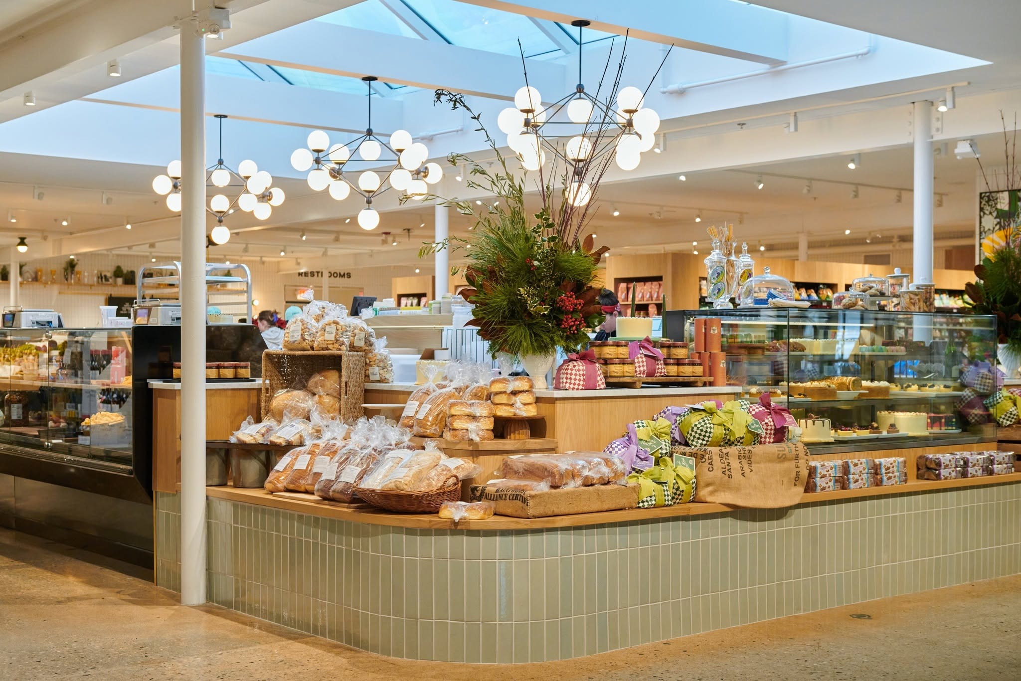 Interior of Littleton’s Market in Upper Arlington, Ohio, featuring a gourmet bakery display with fresh breads, pastries, desserts, and modern globe chandeliers.