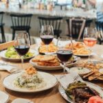 Table filled with gourmet entrées, fresh salads, sandwiches, fries, and glasses of red and rosé wine at Littleton’s Market in Upper Arlington.