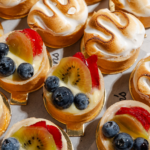 Mini fruit tarts topped with fresh blueberries, strawberries, and kiwi alongside toasted meringue tartlets from Littleton’s Market bakery.