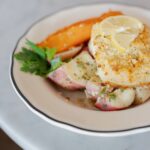Gourmet seafood entrée featuring a golden breadcrumb crust, lemon slices, roasted potatoes, carrots, and fresh parsley at Littleton’s Market.