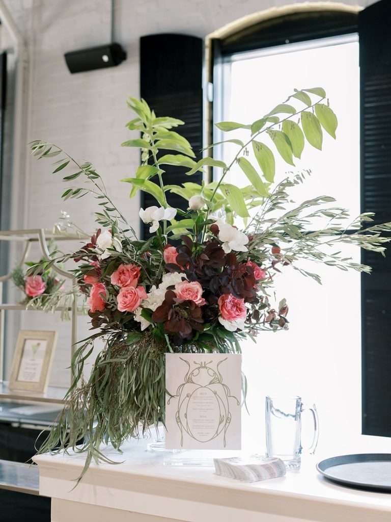 Elegant wedding floral arrangement by Market Blooms in Columbus, Ohio, featuring pink roses, white orchids, burgundy foliage, and lush greenery.