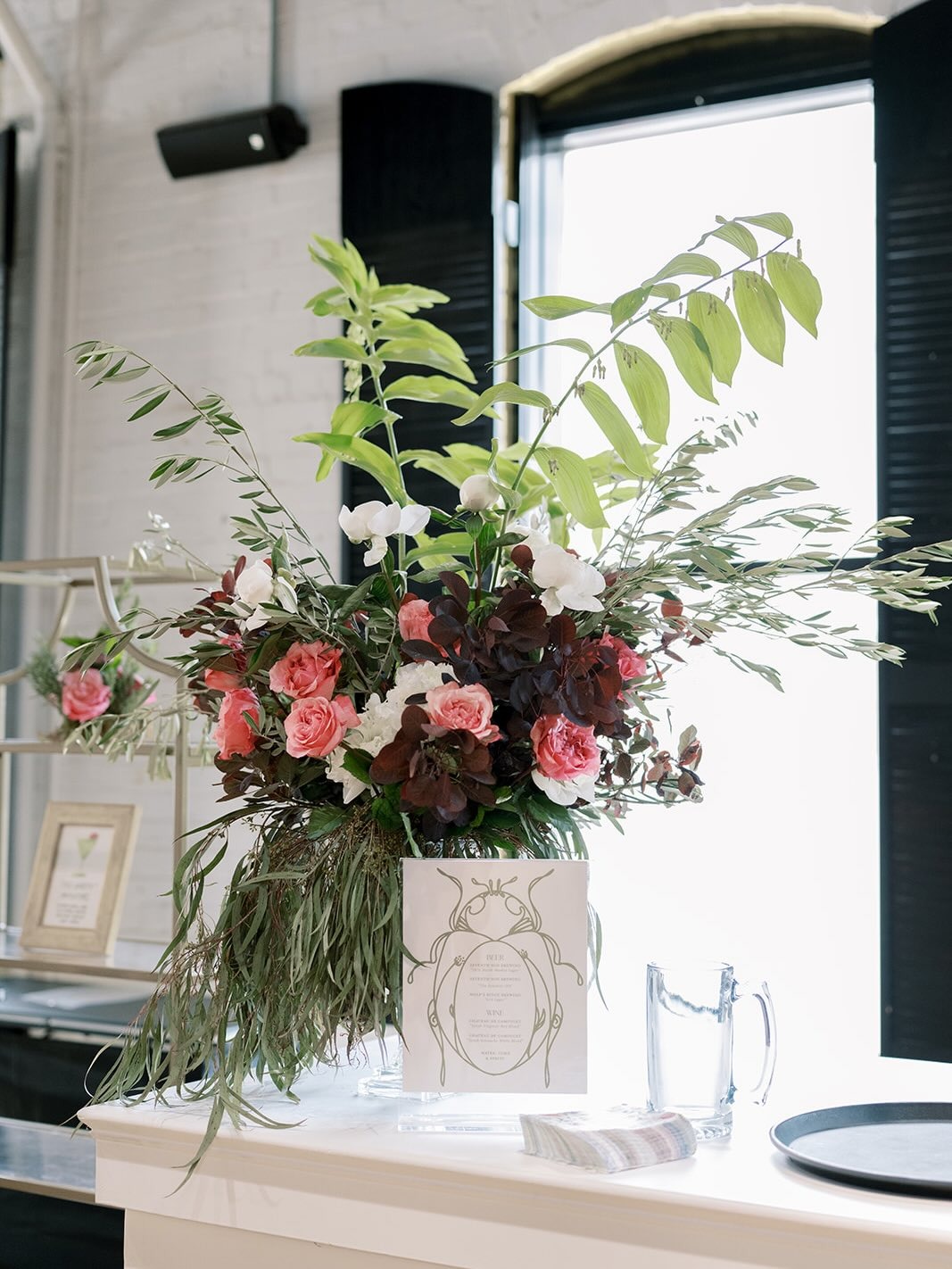 Elegant wedding floral arrangement by Market Blooms in Columbus, Ohio, featuring pink roses, white orchids, burgundy foliage, and lush greenery.