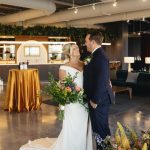 Columbus bride and groom posing with a colorful garden-style bridal bouquet featuring pink, blue, and yellow flowers by Market Blooms.