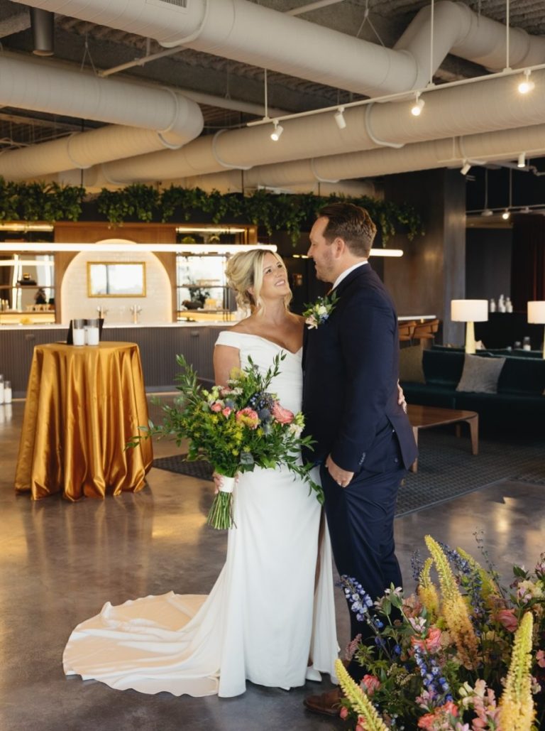 Columbus bride and groom posing with a colorful garden-style bridal bouquet featuring pink, blue, and yellow flowers by Market Blooms.
