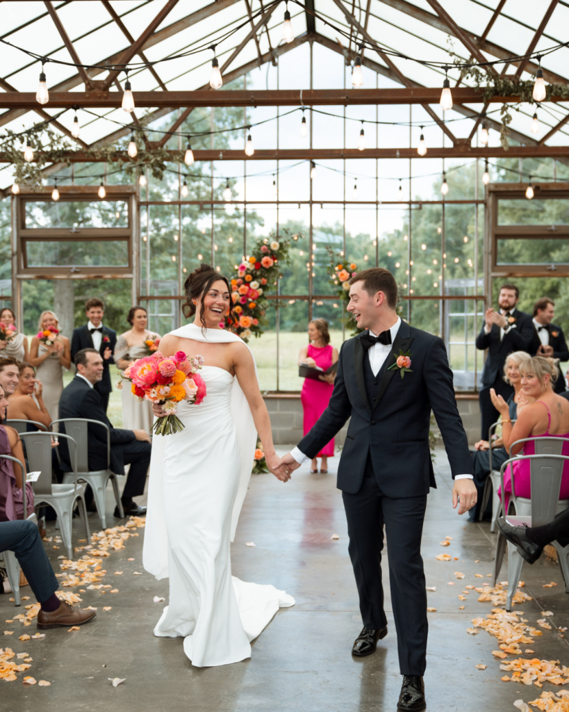 Meghan and Tyler celebrate their wedding ceremony inside the glass greenhouse at Jorgensen Farms Oak Grove in Westerville, Ohio, with colorful florals.
