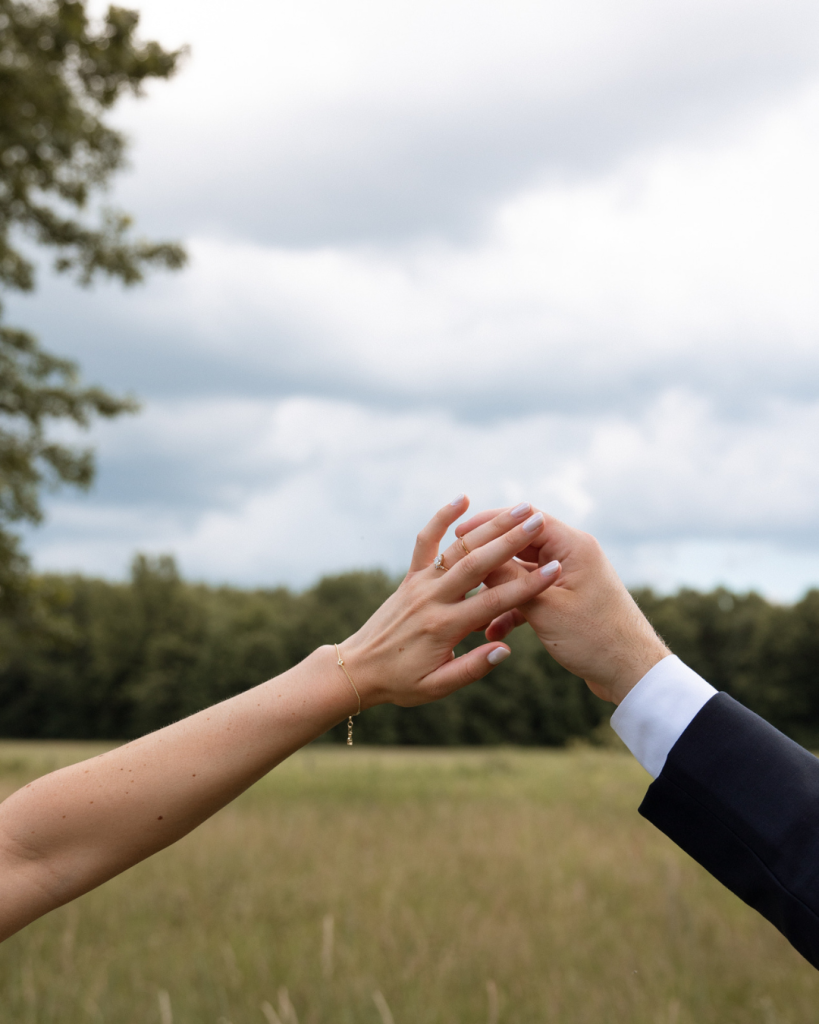 Meghan and Tyler show off their wedding rings while holding hands in a grassy field at Jorgensen Farms Oak Grove in Westerville, Ohio.