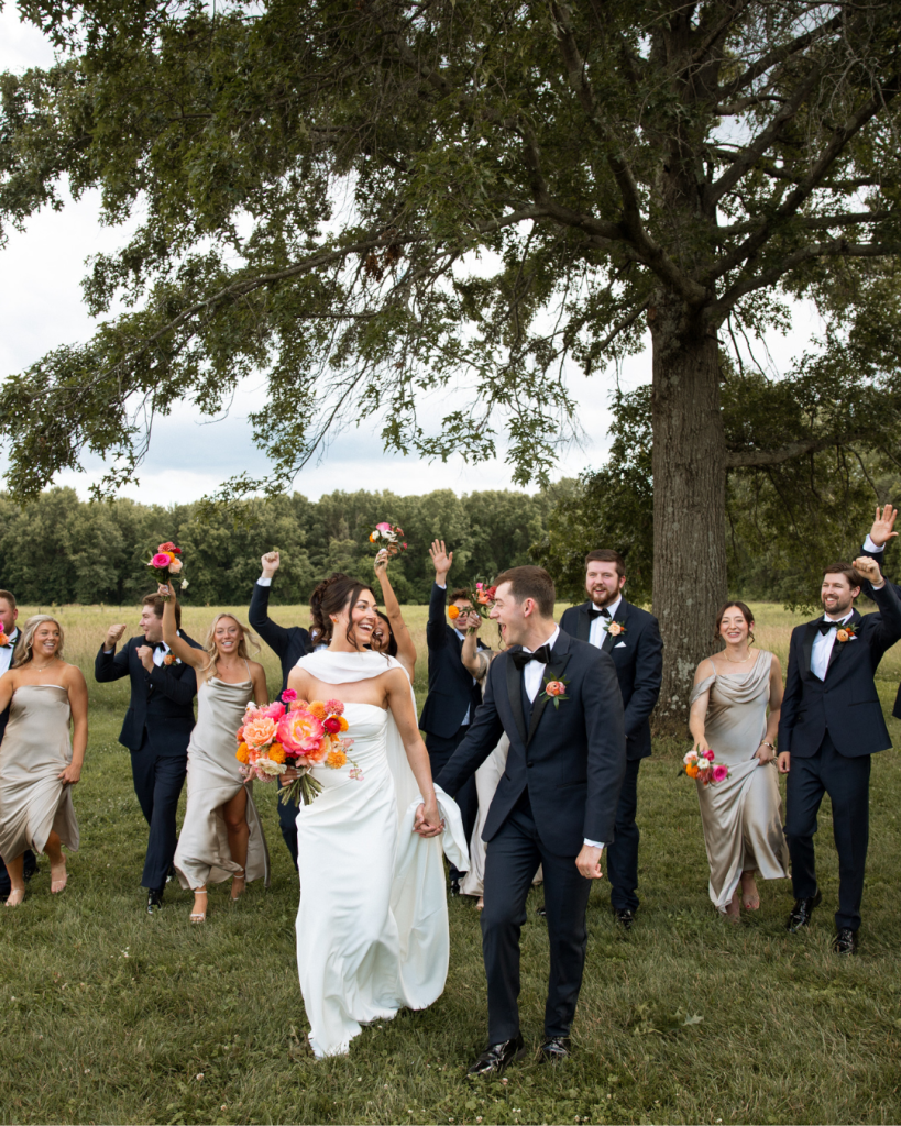 Meghan and Tyler celebrate with their wedding party outdoors at Jorgensen Farms Oak Grove, featuring neutral bridesmaid dresses and colorful bouquets.