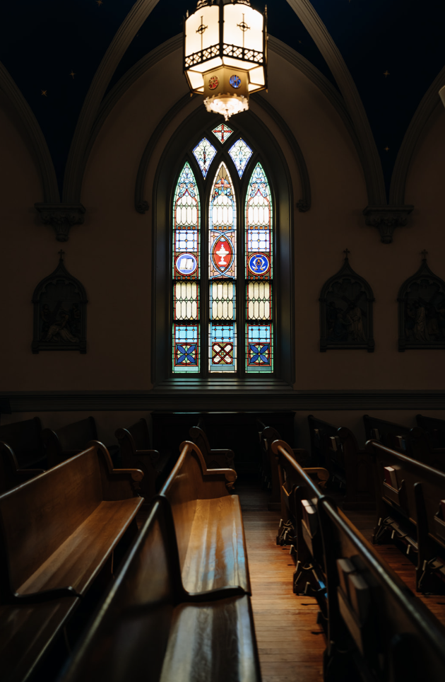 Detailed view of colorful stained glass windows casting light into the church interior.
