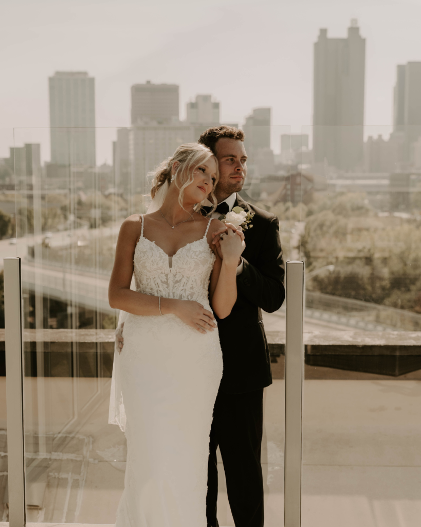 Sydney and Connor share a romantic moment during wedding portraits overlooking downtown Columbus Ohio, with the bride wearing a long veil and elegant lace gown.