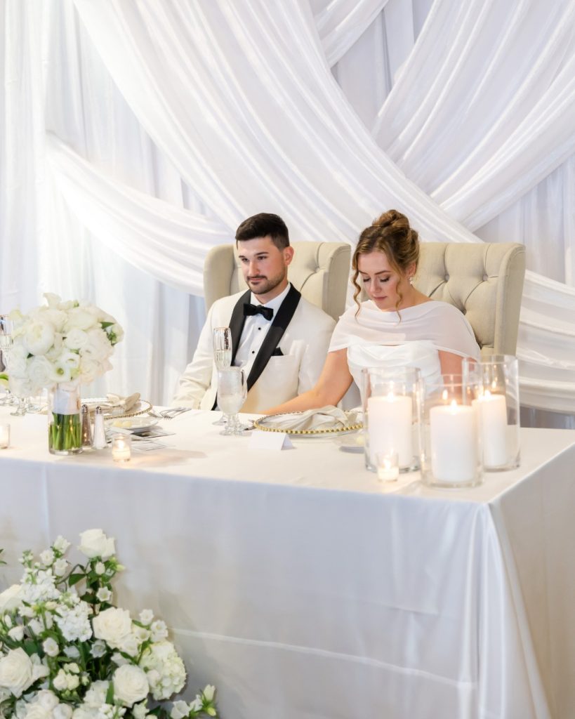 bride and groom couples table with white drapery behind them