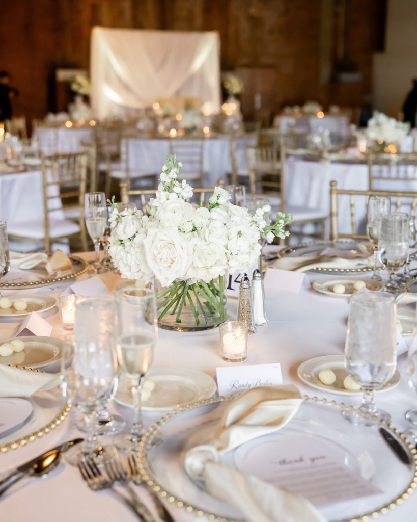 white and gold wedding reception table with gold napkins and white floral centerpiece