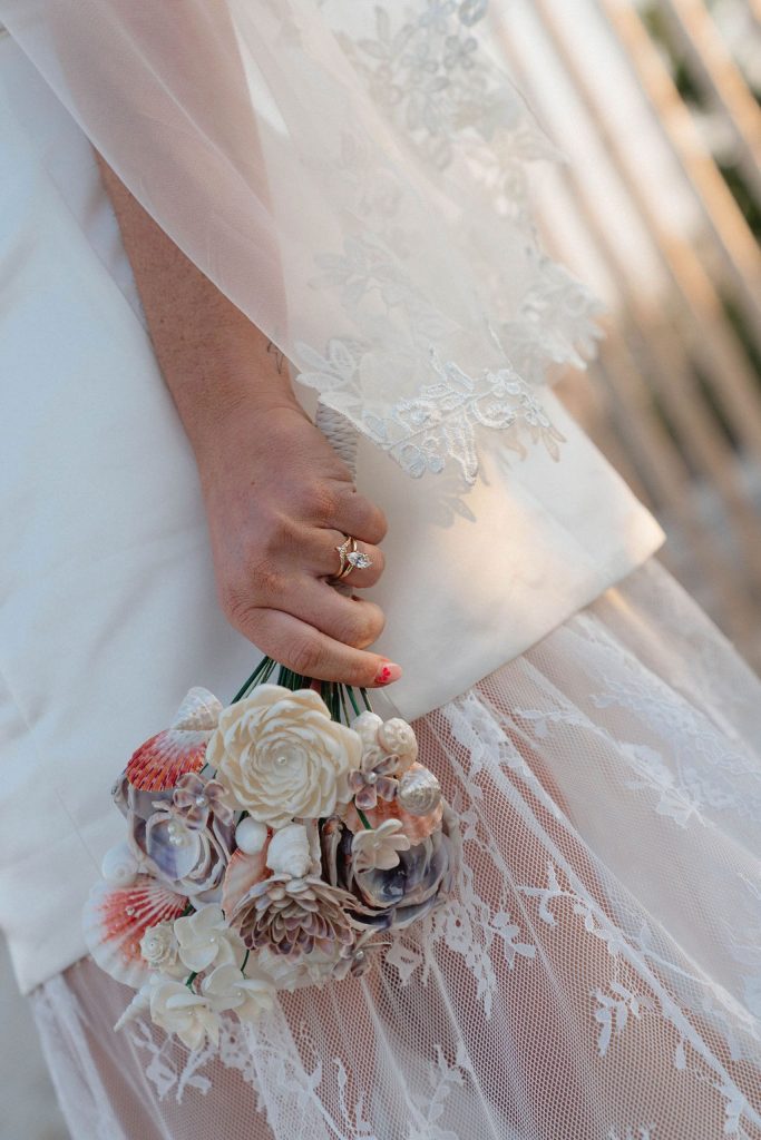 Women in white dress holding flower bouquet and wearing a engagement ring