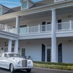 Vintage white getaway car parked outside The Carriage House in Galloway, New Jersey, a white colonial-style South Jersey wedding venue with tall columns, a two-story veranda, and dormer windows, ideal for classic car wedding photos.